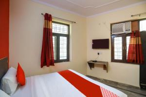 a bedroom with a bed and two windows and a tv at Hotel O Royal Galaxy Inn in Noida