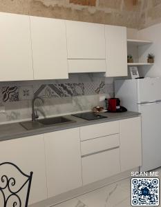 a white kitchen with white cabinets and a sink at Affittacamere Marì in Polignano a Mare