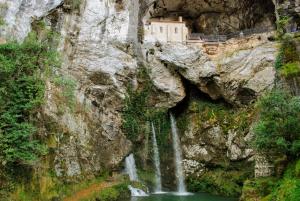 a castle on the side of a mountain with a waterfall at Apartamento La Vega de Santiago 1 in Posada de Llanes