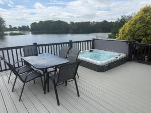 a hot tub on a deck with a table and chairs at Big Duffs Den in Tattershall