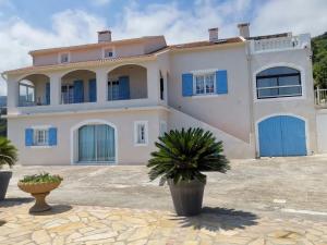 a large white house with blue doors at Appartement Vue Mer à Bastia, terrasse et piscine privée. in Bastia