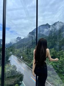 張家界市にあるWARM PLACEのガラス窓から道路を眺める女性