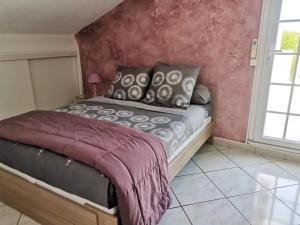 a bed in a bedroom with a pink wall at Appartement Vue Mer à Bastia, terrasse et piscine privée. in Bastia