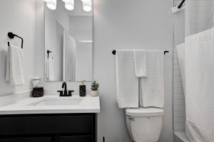 a white bathroom with a sink and a mirror at Specious Luxury wRooftop 1 mi DT Indy Sleeps 6 in Indianapolis