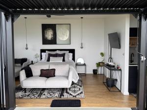 a bedroom with a white bed and a couch at Kauri Lodge -Luxury waterfront in Pouto