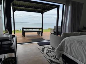a bedroom with a bed and a view of the ocean at Kauri Lodge -Luxury waterfront in Pouto