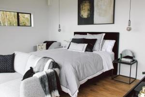 a white bedroom with a large bed and a couch at Kauri Lodge -Luxury waterfront in Pouto