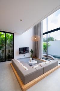 a living room with a large couch and large windows at Villa Chilla - New Modern Loft in Prime Uluwatu in Uluwatu