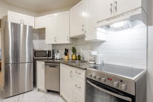 a kitchen with white cabinets and a stainless steel refrigerator at City Verve Modern 2BR in NDG MTL in Montréal