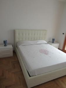a white bed in a bedroom with two night stands at Pianeta Roma 45 in Rome
