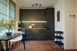 a kitchen with black cabinets and a table with chairs at Entrez Apartment Mlynská Bašta – Košice old center in Košice