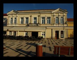 a large building with tables and chairs in front of it at Pe Pe room in Našice