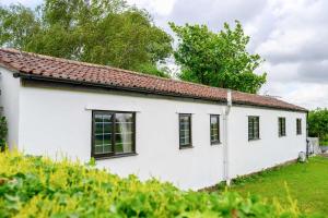 a white house with black windows in a yard at Siston Stables by StayStaycations in Bristol