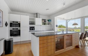 a kitchen with white cabinets and a large window at Five Bedroom Beautiful Home In Sindal in Sindal
