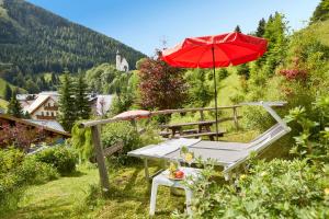 a red umbrella and a picnic table with a bench at Wellnesshotel Mitterwirt in Dienten am Hochkönig
