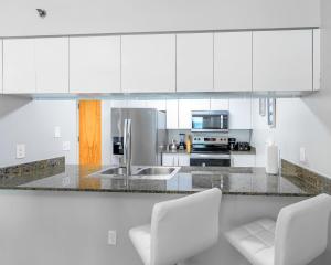 a white kitchen with white cabinets and white chairs at Brickell Condo w City View & Pool Access in Miami