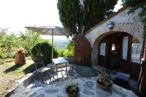 a patio with an umbrella and a table and chairs at Celle di lecchi Porcilaia in San Sano