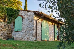an old stone building with green shutters on it at Celle di lecchi Porcilaia in San Sano +1 photo