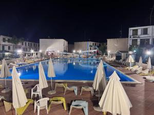 a large swimming pool with chairs and umbrellas at night at Tonzuso Holyday House in Agnone Bagni