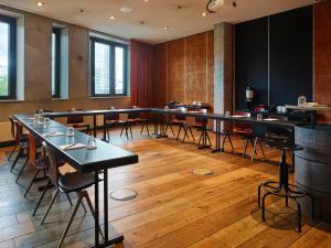 a dining room with tables and chairs and windows at 25hours Hotel Hamburg HafenCity in Hamburg
