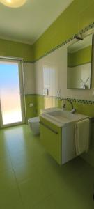 a green bathroom with a sink and a mirror at La casa del Turista Appartment in Gallipoli +32 photos