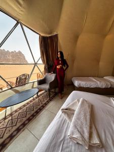 una mujer parada en una habitación con dos camas en Rum Goldeneye luxury camp, en Wadi Rum