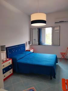Un dormitorio con una cama azul y una ventana. en Balcone sul mare di sciacca, en Sciacca