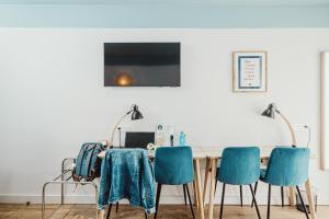 a dining room table with blue chairs and a television at Hotelo Lyon Ainay in Lyon