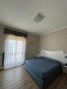 a bedroom with a blue bed and a window at Hotel Giovanna in Pompei