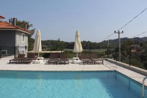 a swimming pool with chairs and umbrellas on a house at Villa Sarisli 3 in Ortaca