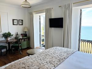 a bedroom with a bed and a balcony with the ocean at Headland View Boutique B&B in Torquay