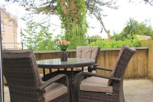 a patio table and chairs with a vase of flowers at Secluded two bedroom apartment in Padstow