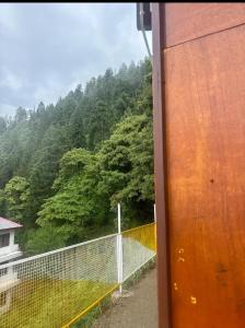 a view from a train window of a fence and trees at Himalayan Wooden Cottage & Cafe Dalhousie in Dalhousie