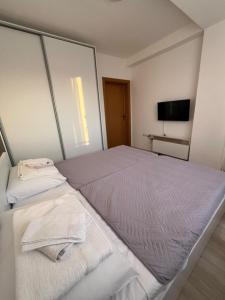a white bedroom with a large bed and a television at Gabi's Cozy Corner in Kumanovo