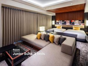 a hotel room with two beds and a couch at Mitsui Garden Hotel Kanazawa in Kanazawa