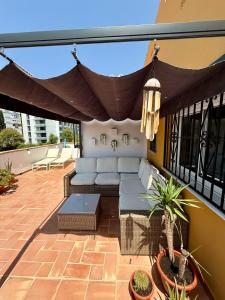 eine Terrasse mit einem Sofa und einem Baldachin auf einem Balkon in der Unterkunft Penthouse - Beach - Sea View - Pool - 40 sqm Private Terrace - One Bedroom - Sleeping Alcove in Benalmádena