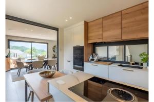 eine Küche mit weißen Schränken und ein Esszimmer mit einem Tisch in der Unterkunft Villa proche Lac in Écharvine