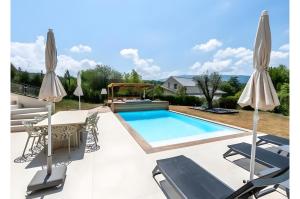 einen Pool mit Gartenmöbeln und Sonnenschirmen in der Unterkunft Villa proche Lac in Écharvine