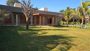 a house with palm trees in front of a yard at Chácara Recanto dos Pássaros 04 in Olímpia