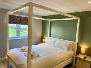 ein Schlafzimmer mit Himmelbett und Fenster in der Unterkunft Stylish 3-Bed Seaview Retreat with Balcony - Steps from the Beach - Westward Ho! in Westward Ho