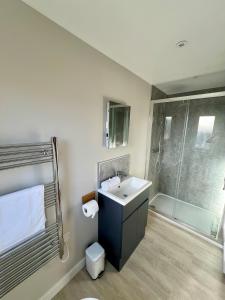 ein Badezimmer mit Waschbecken und Dusche in der Unterkunft Stylish 3-Bed Seaview Retreat with Balcony - Steps from the Beach - Westward Ho! in Westward Ho
