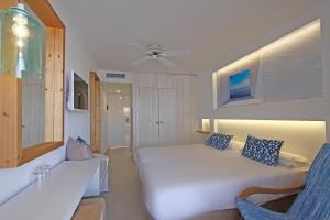 - une chambre avec un lit blanc et une chaise bleue dans l'établissement BG Portinatx Beach Club Hotel, à Portinatx