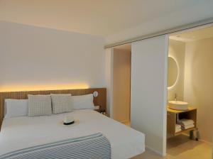 Un dormitorio con una cama blanca y un espejo. en MYO Barcelona Hotel & Apartments, en Castelldefels