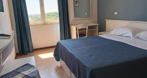 a bedroom with a bed and a table and a window at Hotel Club Perla in Casalabate