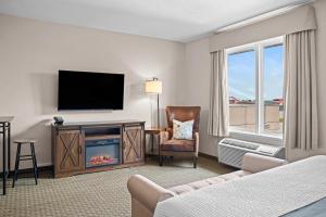 a living room with a fireplace and a television at Days Inn & Suites by Wyndham Winkler in Winkler