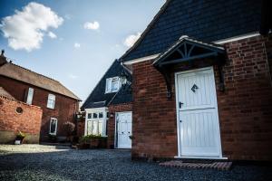 a brick building with white doors and a roof at Annex at The Stables in the Heart of England in Hinckley