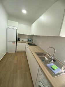 a white kitchen with a sink and a refrigerator at Beachside Getaway in Zapillo in Almería