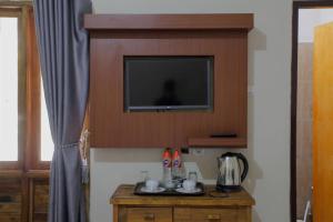 Habitación con TV en la pared y mesa. en New Dgyp Ciater Resort, en Ciater