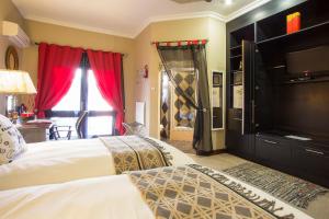 a bedroom with two beds and a flat screen tv at The Royal Palm B&B in Ohrigstad