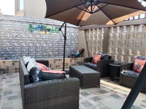a patio with two wicker chairs and an umbrella at MC One Stop Road Lounge Hotel in Xai-Xai